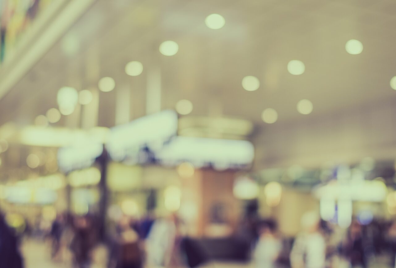 Travellers crossing a busy airport departures hall.